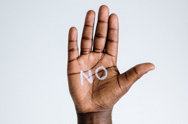 Black Hand raised up with palm facing outwards and “No” written on it in white letters, to represent prevention in substance use.